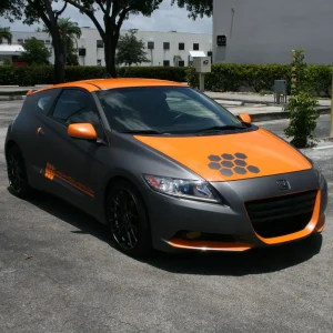 A grey coupe car wrapped with orange graphics and highlights